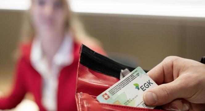 Ein Mann nimmt seine Krankenkassenkarte aus dem Portemonnaie am Empfang des Physiozentrum Baden, fotografiert am Dienstag, 12. Maerz 2024 in Baden. (KEYSTONE/Christian Beutler)
