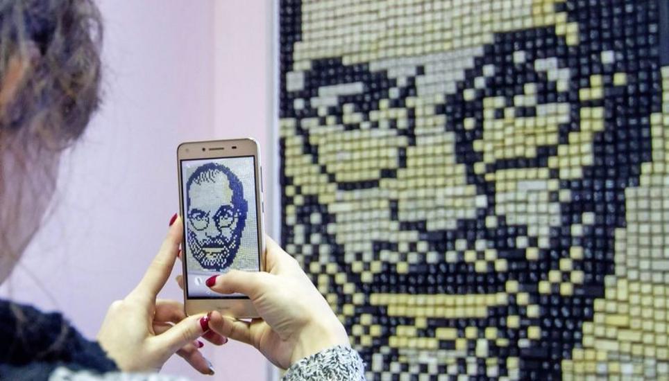 Der im Jahr 2011 verstorbene Apple-Chef Steve Jobs hat mit dem iPhone unser aller Leben verändert. Ukrainische Studenten haben aus Computertastaturstücken sein Porträt kreiert – eine junge Frau fotografiert es mit ihrem Smartphone. Bild: Key