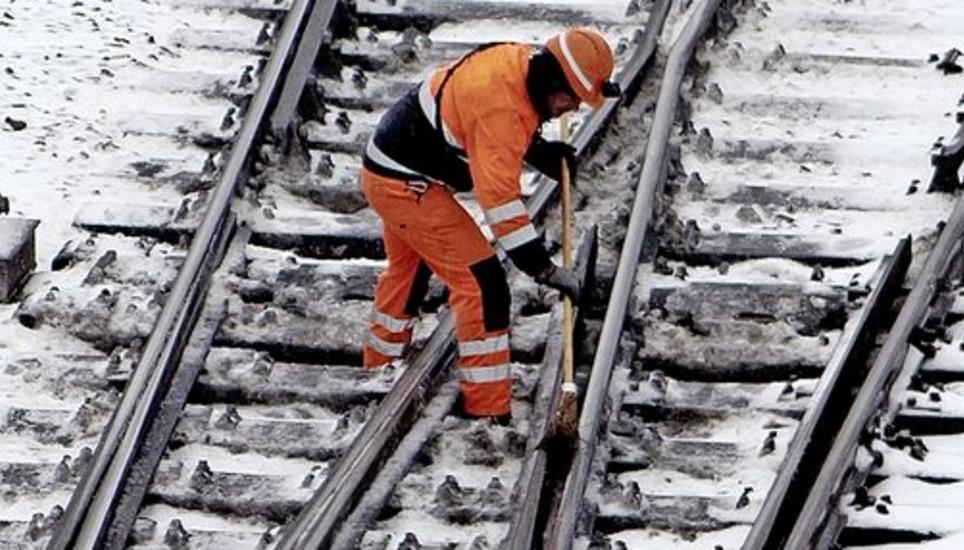Ein Arbeiter befreit Gleise von Eis und Schnee. Bild: Key