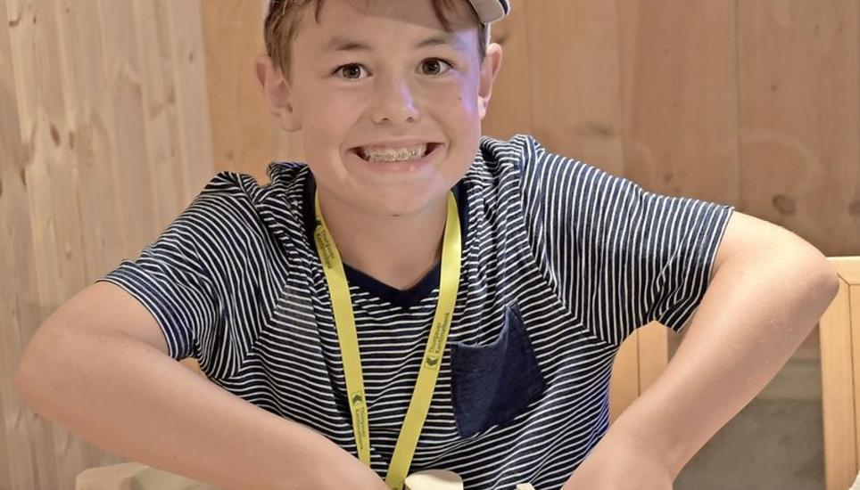 Jasper drückt seine Tonplatte mit Spachtel und Fingern platt.