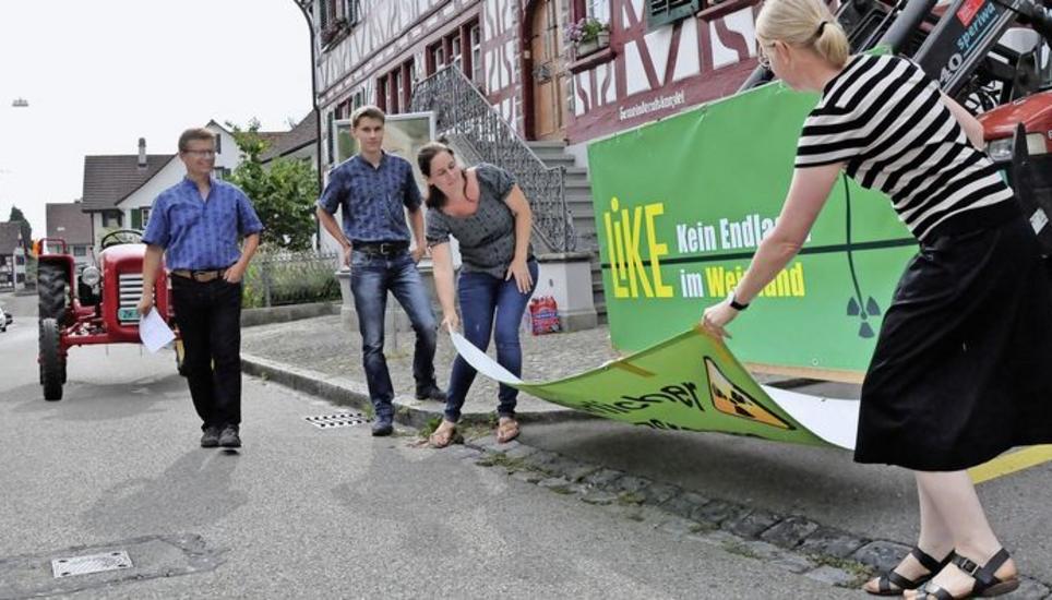Der designierte Präsident Jürg Rasi (l.) schaut mit seinem Sohn Samuel zu, wie Ehefrau Rachel (Mitte) und Britta Reich das neue Vereinslogo am Traktor enthüllen. Bild: Mark Gasser