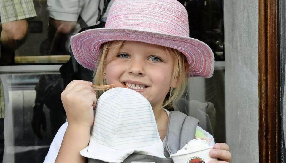 Elin und ihre Puppe tragen beide einen Sonnenhut, während sie sich bei dieser Hitze eine Glace gönnen.