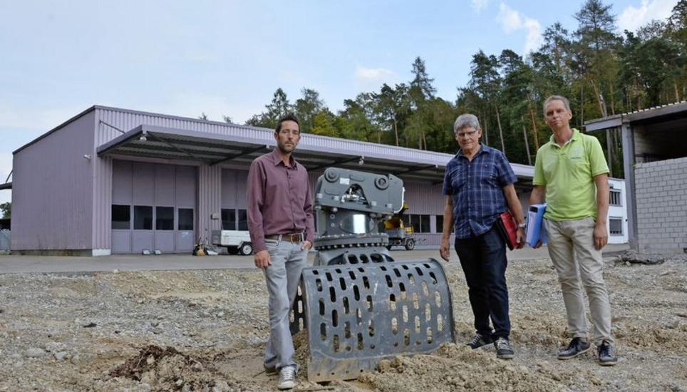 Wo der Greifer steht, soll eine neue Einstellhalle entstehen. Patrick De Quervain (Leiter Hochbau), Gemeinderat Ruedi Meier und Thomas Müller (Leiter Tiefbau, von links) auf dem künftigen Neuhauser Werkhofareal. Bild: Saskia Baumgartner