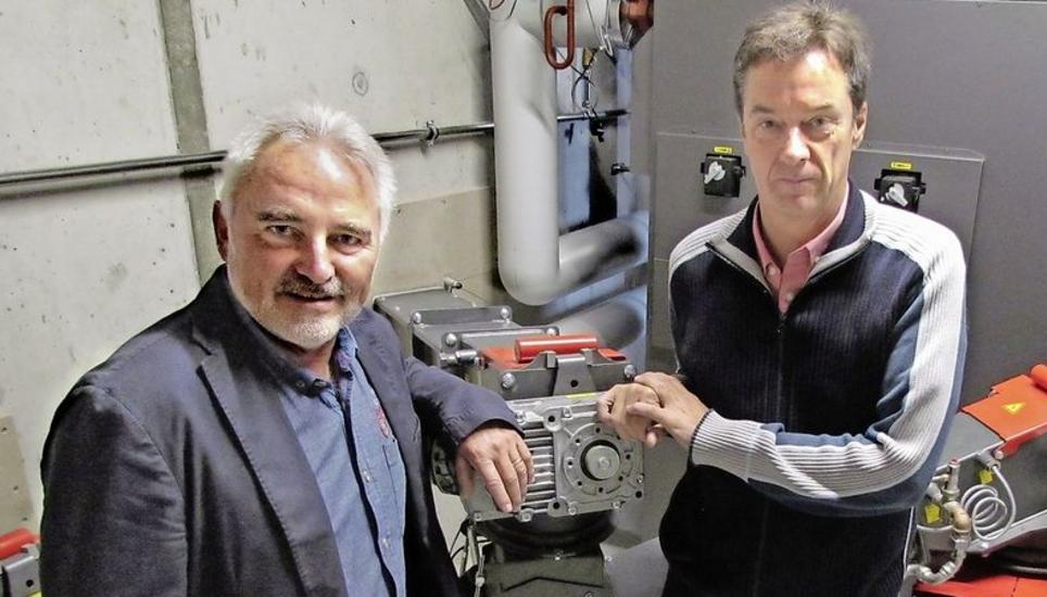 Gemeindepräsident Claus Ullmann (links) und Projektleiter Philippe Rimbeaux vor einem der neuen Heizöfen mit den Anschlüssen der Schnitzelkanäle. Bild: Ernst Hunkeler