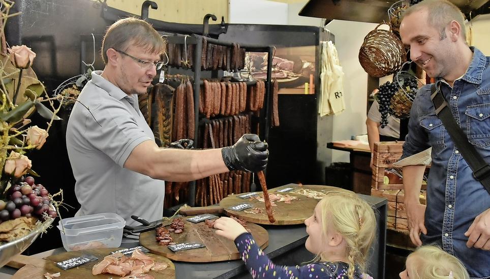 Die Rauchfleischspezialitäten aus dem Zürcher Weinland locken viele Olma-Besucher an. Vor vier Jahren übernahm Roman Schmid (links) die Firma Rubli aus Marthalen. Die beiden Mädchen aus Amriswil lassen es sich schmecken. Bild: Miriam Barner