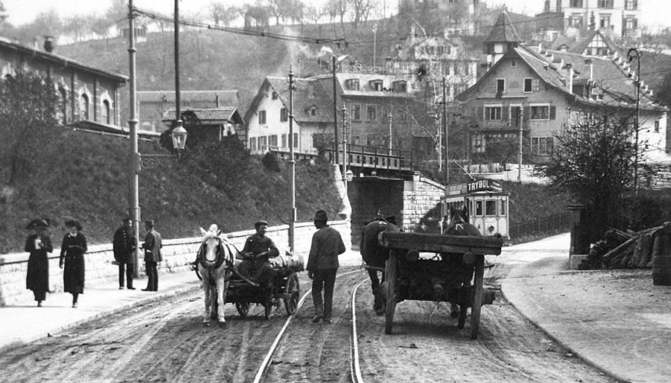Pferdefuhrwerke treffen im Jahr 1912 bei der Haltestelle Cardinal auf die etwas modernere Strassenbahn.