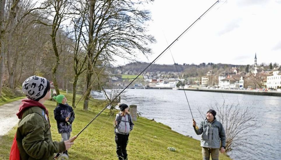 Der geübte Fischer Tom Zimmermann (rechts) zeigt den Kindern am Rheinufer, wie eine Angelrute richtig benutzt wird. Er selbst fischt seit rund 25 Jahren. Sein Wissen gibt er deshalb am Jungfischerkurs weiter und versorgt die Interessierten mit praktischen Tipps und Tricks. Bild: Selwyn Hoffmann