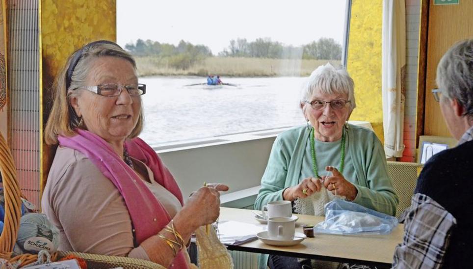 Während auf dem Wasser ein Achter mit Steuermann vorbeirudert, geniessen die Strickerinnen die gemütliche Schifffahrt. Bilder: Theo Kübler