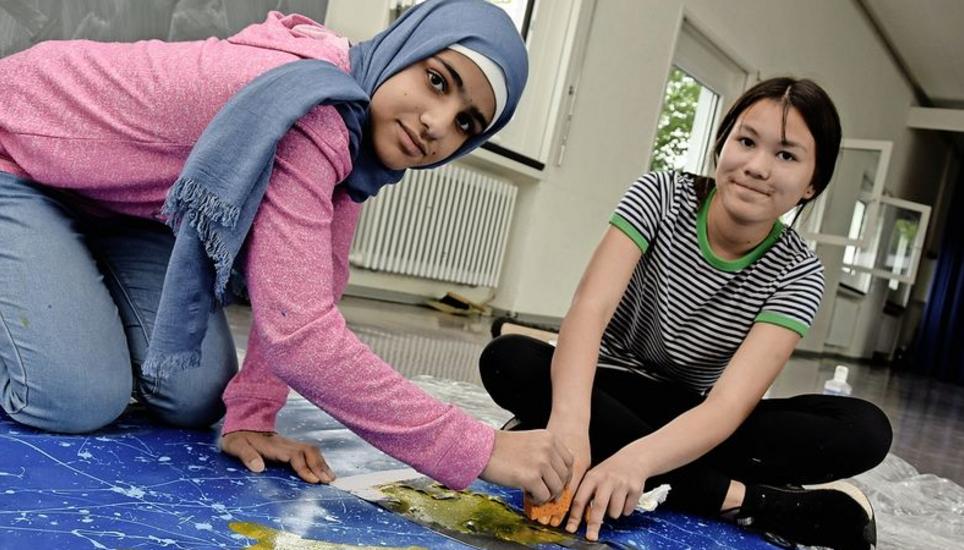 Mit einem Schwamm tupfen Marva und Katelyn gelbe Farbe auf ihr Plakat. Es wird später die Aula zieren. Bild: Melina Ehrat