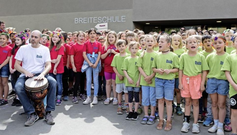Die Schulkinder singen vor dem Schulhauseingang das Einstiegslied zur Eröffnung. Bild: Phillip Schmanau