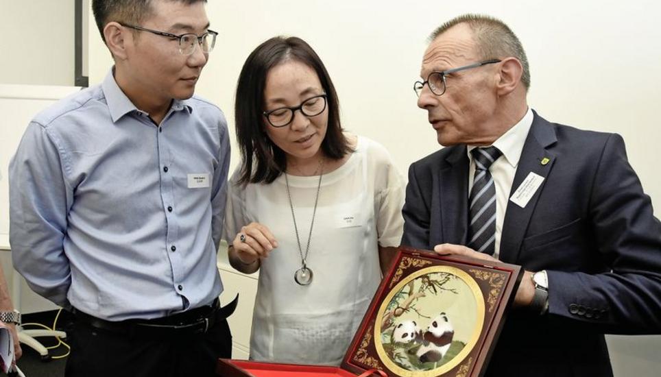 Delegationsleiter Qinghui Peng (l.), Übersetzerin Xia Chen und Regierungspräsident Ernst Landolt mit dem Geschenk der chinesischen Delegation: Die Seidenstickerei ist ein für die Provinz Hunan typisches Produkt. Bild: Melina Ehrat