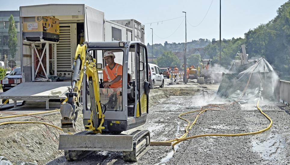 Diesem Bauarbeiter bietet das Dach des Baggers bei der Hitze ein wenig Schatten – aber auch sonst wird für Sonnenschutz auf der Baustelle gesorgt. Bild: Selwyn Hoffmann