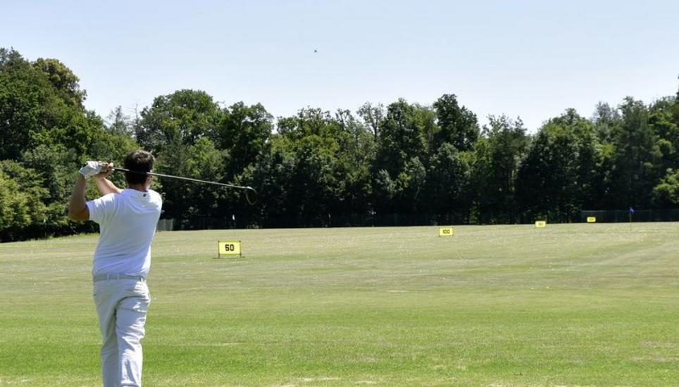 Der Golflehrer führt einen Abschlag auf der Driving Range vor.