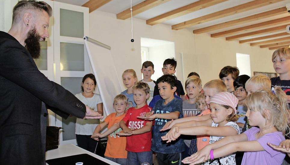René Schenkel zeigt den Kindern, wie sie die Hände halten müssen damit die Täuschung gelingt. Bild: Stefan Salzmann