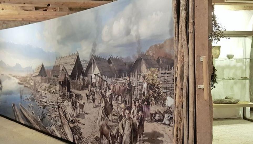 Das raumfüllende Bild eines Pfahlbaudorfs am Morgen nach dem Sturm, dahinter Vitrinen der Kantonsarchäologie. Bild: schi