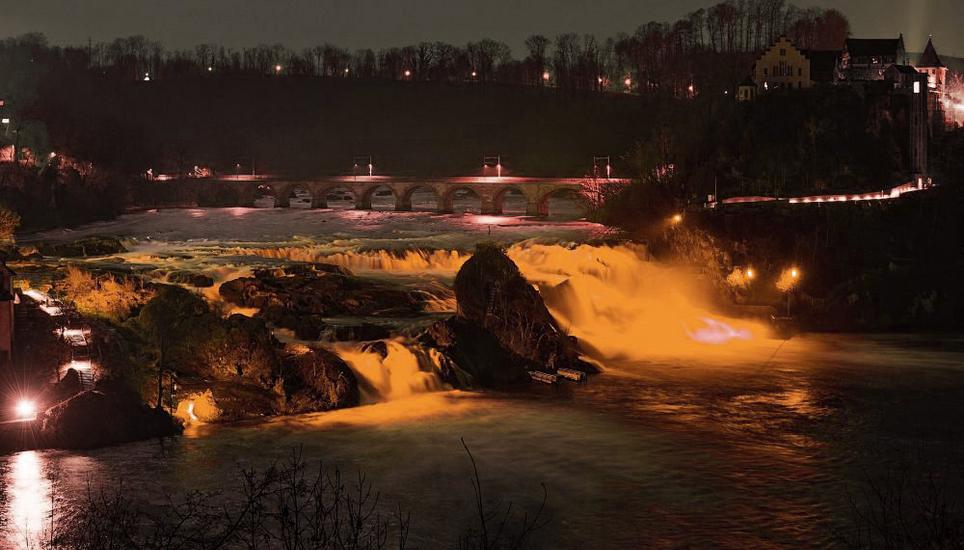 Der Rheinfall soll heute Abend zum ersten Mal orange erleuchtet werden. Bildmontage: Lara Galliker