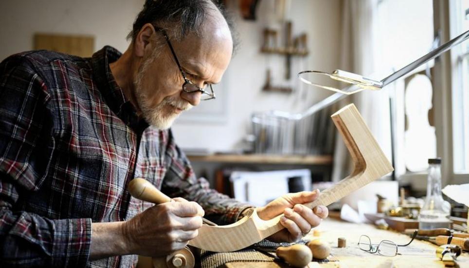 Gemeinsam mit Frau Michèle arbeitet Martin Kuhn an Reparaturen und Neubauten von zahlreichen Streichinstrumenten. Hier ist er gerade mit der sogenannten Schnecke eines Cellos beschäftigt.