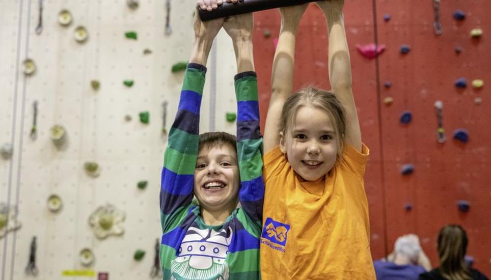 Kiana und Yanik Fuchs hängen lachend von der Trainingsstange in der Kletterhalle im Ebnat.
