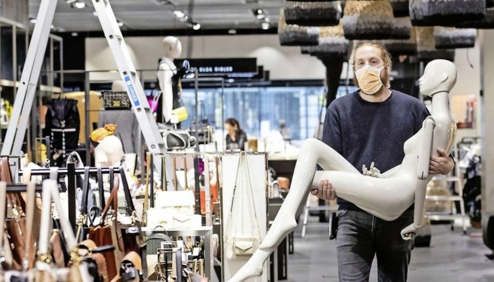 Die Maske ist Teil der Corona-Exit-Strategie: Ein Mitarbeiter des Dekorationsteams läuft mit einer Schaufensterpuppe durch den Globus in Zürich. Bild: Key