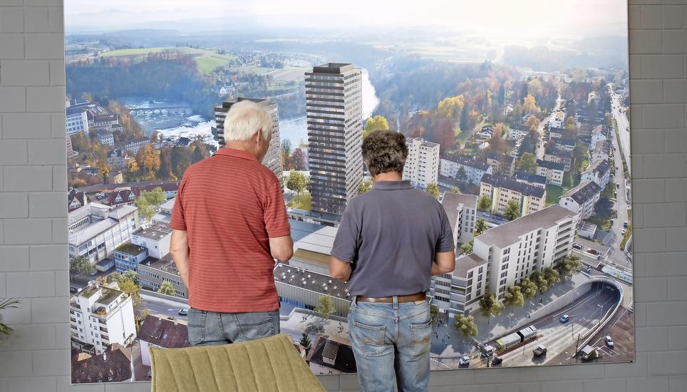 Zwei Besucher bestaunen auf dem Rhytech-Areal die Visualisierung des Gebäudekomplexes mit dem Rhyfalltower (Mitte) und dem Rhygarten (rechts). Bild: Alexander Joho