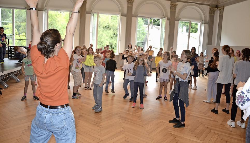 Chorleiterin Sophie Ehrismann wärmt sich mit den Schülerinnen und Schülern der Musikschule Schaffhausen bei ein paar Bewegungs- und Singübungen auf. Nach langer Zeit sehen sich die Chor-Gspänli wieder. Bild: Larissa Ruh