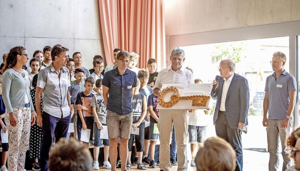 Eine Schlüsselübergabe der besonderen Art: Monika Schlatter, Beat Steinacher, Marcel Zürcher, Ruedi Meier, Stephan Rawyler und Thomas Wirz (v.l.n.r.) in der neuen Aula des Schulhauses Kirchacker. Bild: Roberta Fele