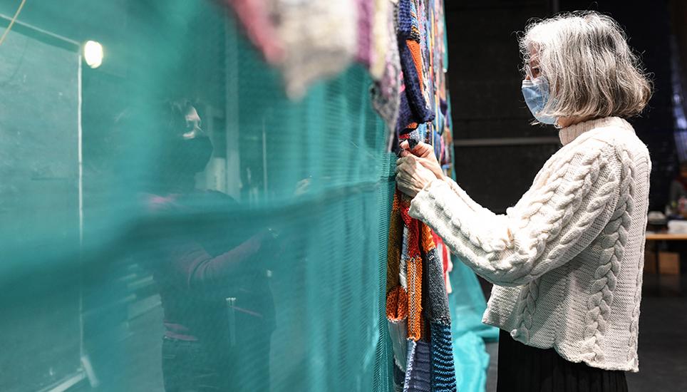 Ein Teppich als grosses Gemeinschaftswerk: Freiwillige befestigen die gestrickten Quadrate im Stadttheater an einer Blache. Bild: Melanie Duchene