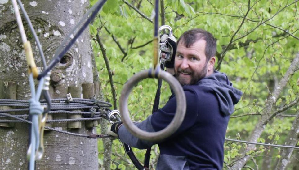 An zwei Ringen baumelnd rutscht Beat Schuppisser von einer Baumplattform zur andern. Bild: Dominic Caviezel
