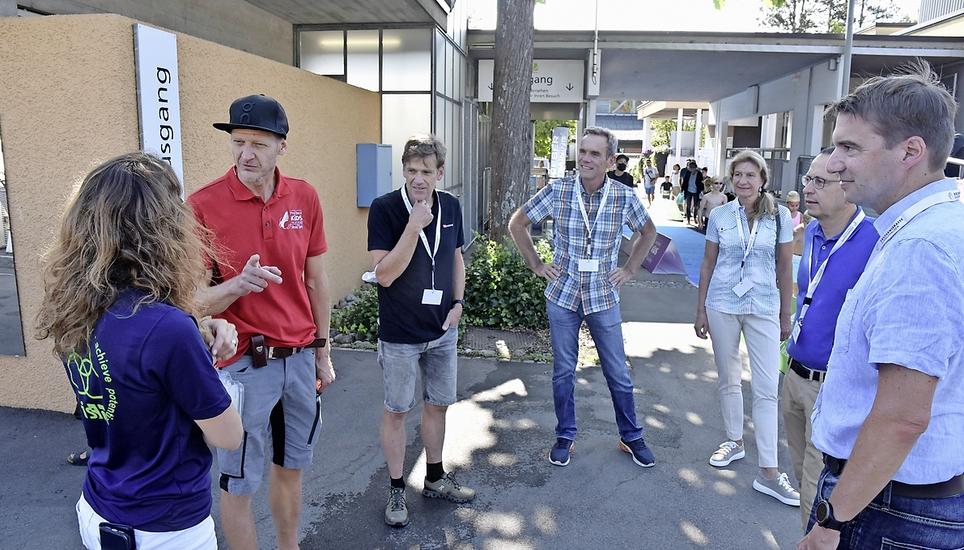 Reto Hug (2. v.l.), der Ehemann der Kids-Triathlon-Gründerin Nicola Spirig, erklärt den Gästen die Abläufe: OK-Chef Marcel Zürcher, Marko Altmann mit Ehefrau Sandra, Christian Ritzmann und Regierungsrat Patrick Strasser (v.l.).