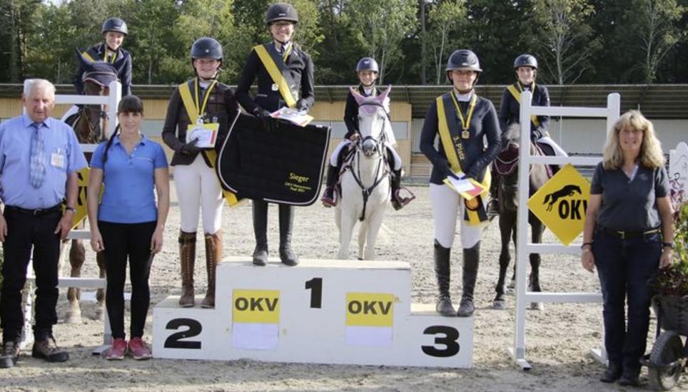 Die Podestplätze der Newcomersmeisterschaft Springen (beritten kleine Tour/unberitten grosse Tour) umrahmt von (v. l.) Vinzenz Gehrig (Jurypräsident), Melanie Schmid (OK-Präsidentin) und Dominique Suter (Chefin OKV-Nachwuchsförderung). Bild: Kue