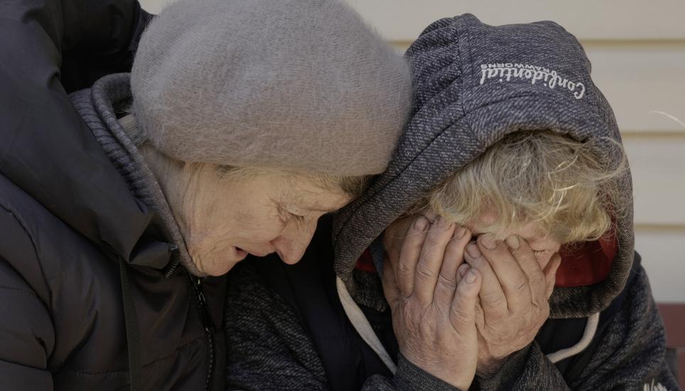 Eine Frau trauert in Butscha um ihren Ehemann und ihren Neffen, die von russischen Truppen getötet wurden. Eine Nachbarin spendet Trost (Bild vom 4. April). Bild: Key