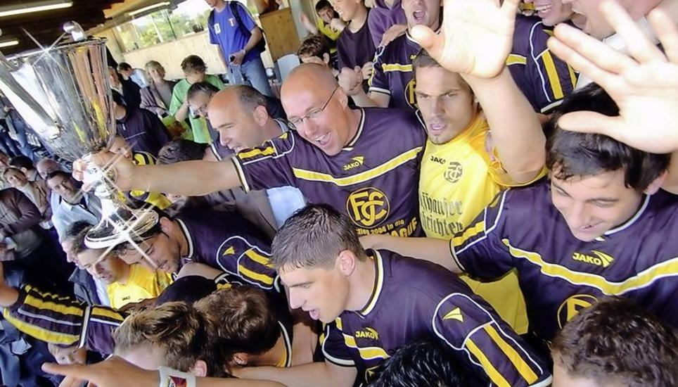 Hoch den Pott: Aufstiegstrainer Jürgen Seeberger (Mitte, mit Pokal) streckt stolz den Meisterchübel in die Höhe. Zusammen mit den Spielern und den Fans wurde im Anschluss ausgiebig der Aufstieg gefeiert. Bild: Michael Kessler