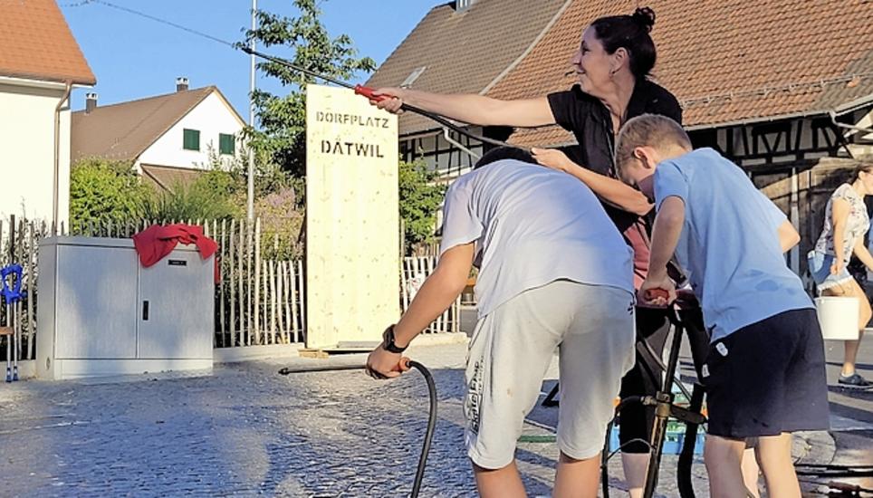Mit einer Wassertaufe weihen Anwohner ihren neuen Dorfplatz ein. Bild: mrö