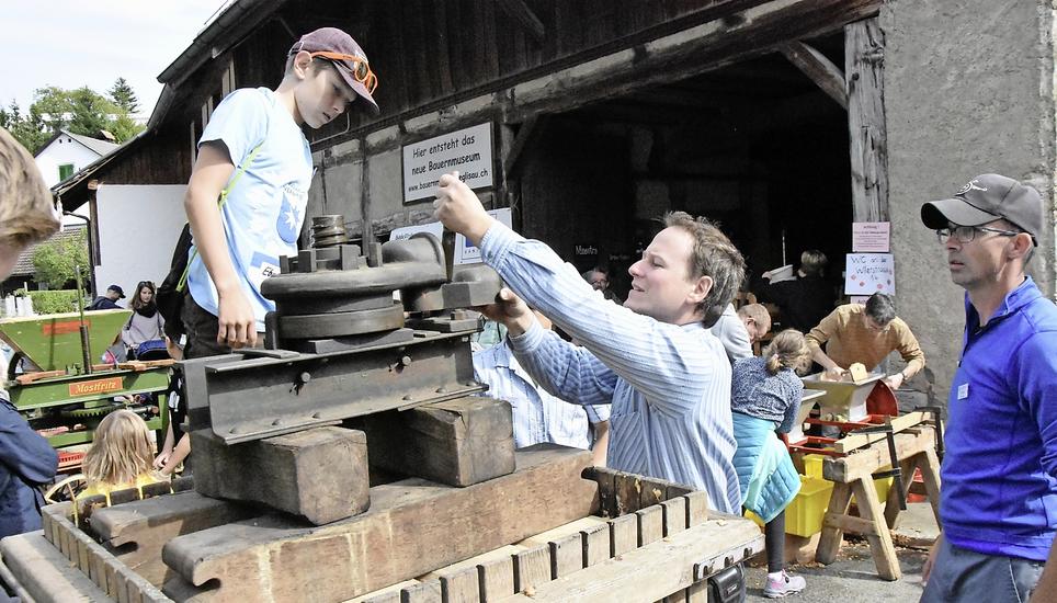 Der Museumsleiter Thomas Koch (M.) zeigt, wie die Pressmaschine funktioniert. Bild: Mirza Hodel