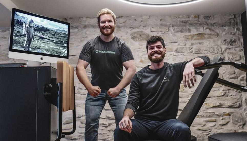 Aurum-Gründer Julian Massler (l.) und Franchise-Nehmer Tom Reunis posieren auf ihrem Fitnessgerät. Ein Training dauert grade einmal 20 Minuten. Bild: Melanie Duchene