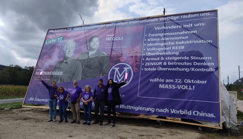 Das Plakat, das weg muss und die Mass-Voll-Anhänger um Nicolas Rimoldi (rechts). Bild: Sandy Hedinger