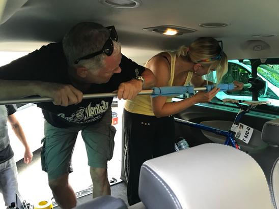 Roger und Karin befestigen eine Duschstange im Auto - als Veloständer.