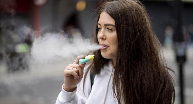 epa10663278 A person uses a single-use vaping product in London, Britain, 30 May 2023. The UK government has announced it is cracking down on retailers providing free vape samples to children. The government's new proposals include rules on fines for shop