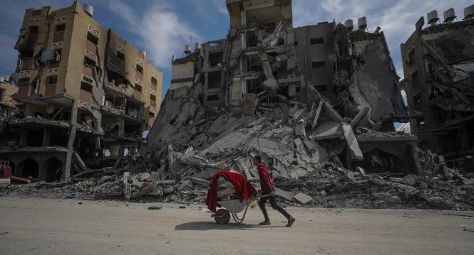 epaselect epa11220424 A Palestinian man pushes a wheelbarrow past the rubble of destroyed houses at Hamad towers city following an Israeli military operation in Khan Younis town, southern Gaza Strip, 14 March 2024. More than 31,000 Palestinians and over 1