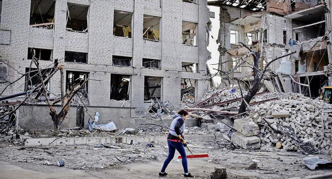 A local resident clears debris near a building damaged in the Russian air raid in the town of Orikhiv, Zaporizhzhia region, Ukraine, Friday, Apr. 5, 2024. (AP Photo/Andriy Andriyenko)