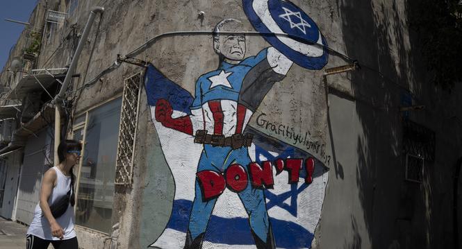 CORRECTS TO WOMAN - A woman walks past a mural depicting U.S. President Joe Biden as a superhero defending Israel on a street in Tel Aviv, Israel, Sunday, April 14, 2024. Israel on Sunday hailed its successful air defenses in the face of an unprecedented 