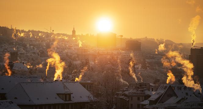 Rauchsaeulen von Kaminen waehrend dem Sonnenaufgang, fotografiert am Sonntag, 3. Dezember 2023 in Zuerich Wipkingen. (KEYSTONE/Christian Beutler)