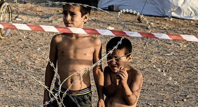 epa08682485 Two small boys stand behind razor wire at Kara Tepe camp on Lesbos island, Greece, 19 September 2020. Following the catastrophic fires at Moria on September 8 and 9, a total of 9,000 people were rehoused at the hotspot of Kara Tepe, south of M